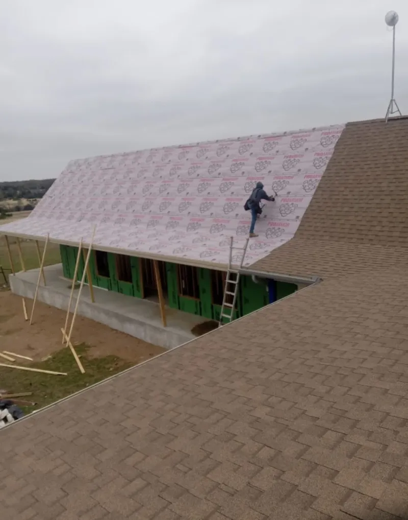 Worker preparing underlayment for a metal roof installation in Manor